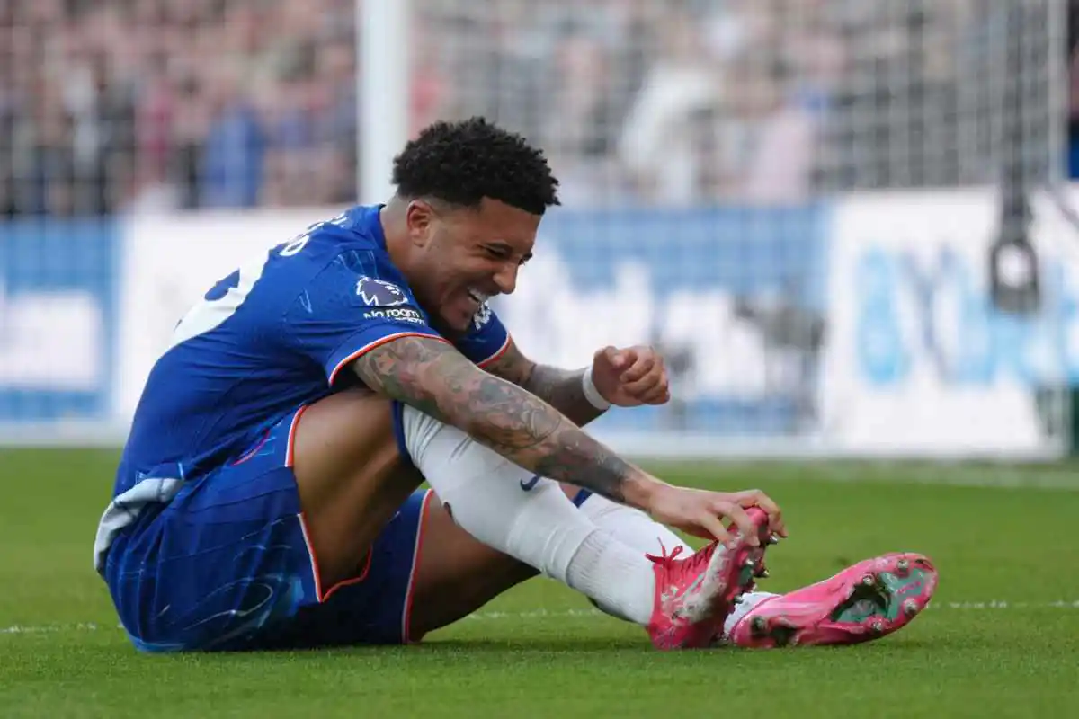 Sancho seduto sul terreno di gioco con indosso la maglia del Chelsea