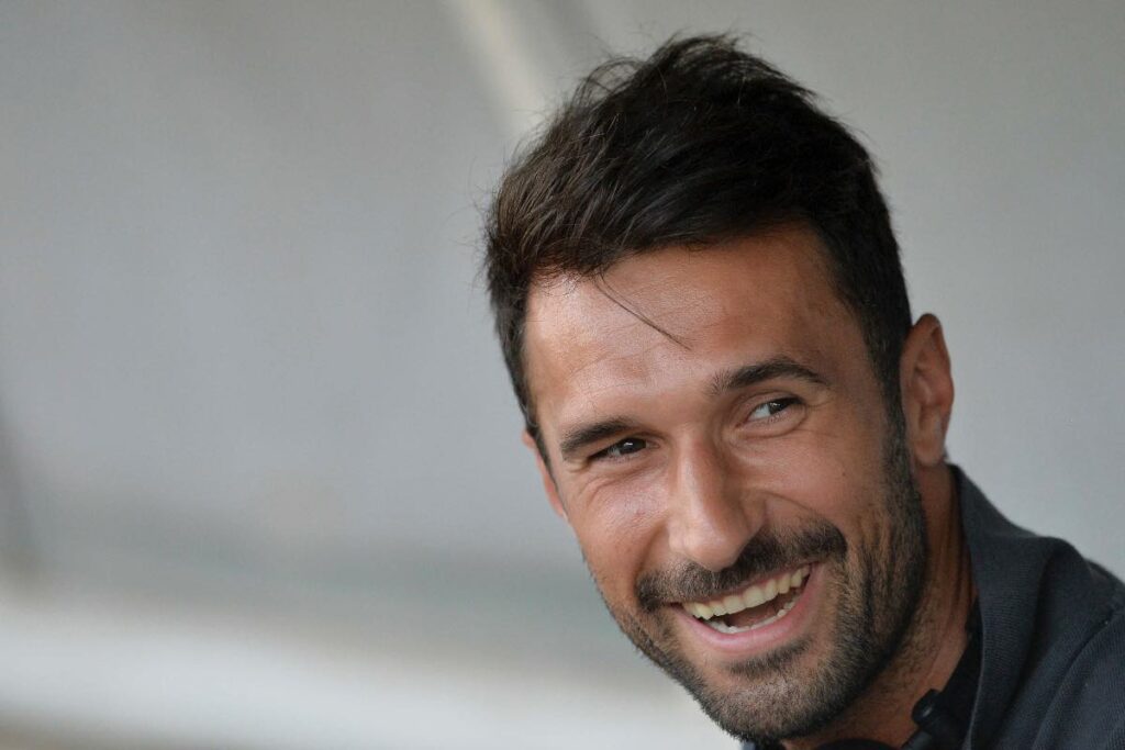 Mirko Vučinić sorride nel 2025, ritratto a bordo campo durante una sessione di allenamento con la Juventus.