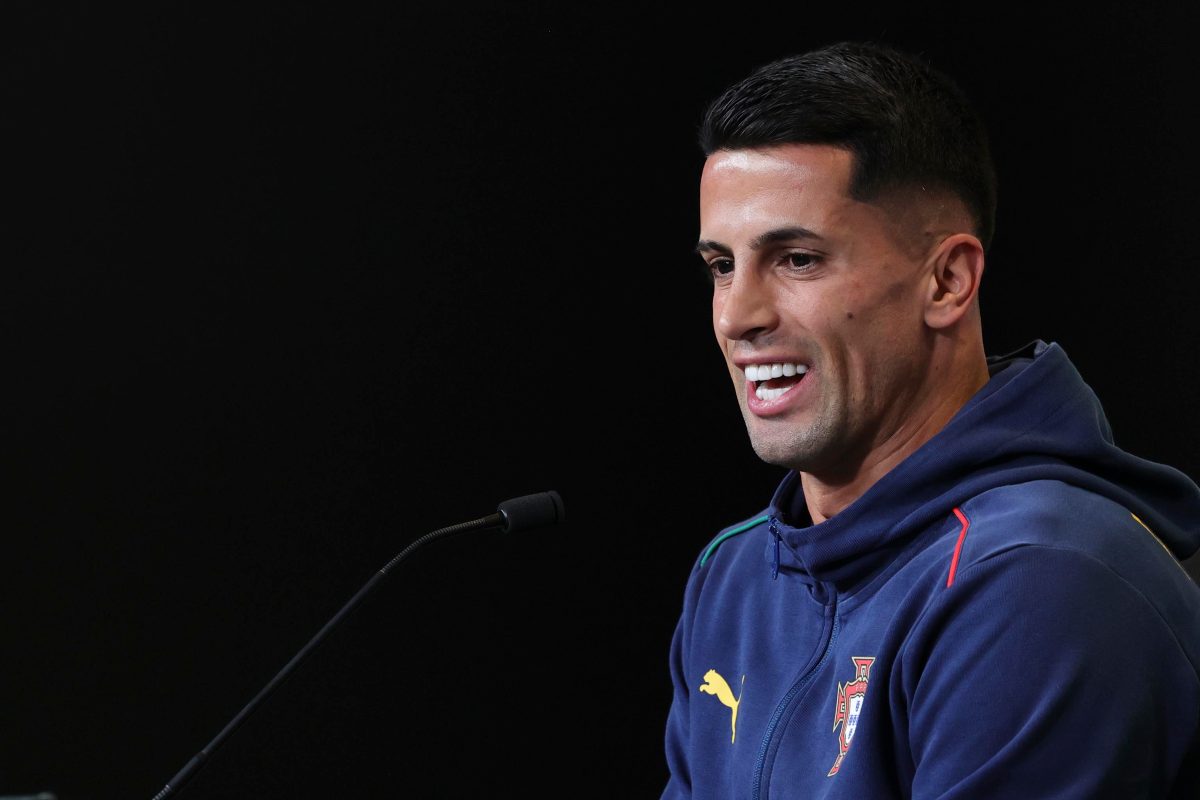Joao Cancelo sorride in conferenza stampa con la tuta del Portogallo