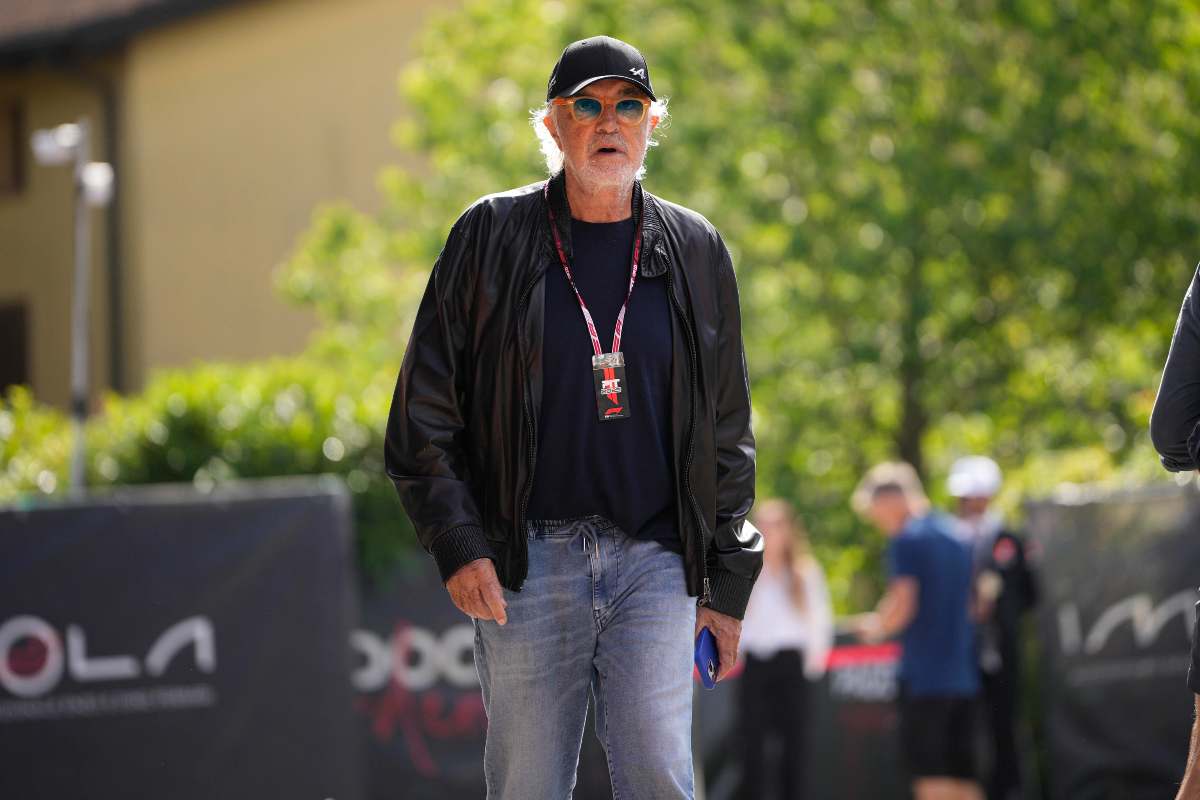 Briatore che cammina in un’area esterna durante un evento pubblico, con badge al collo e outfit casual.