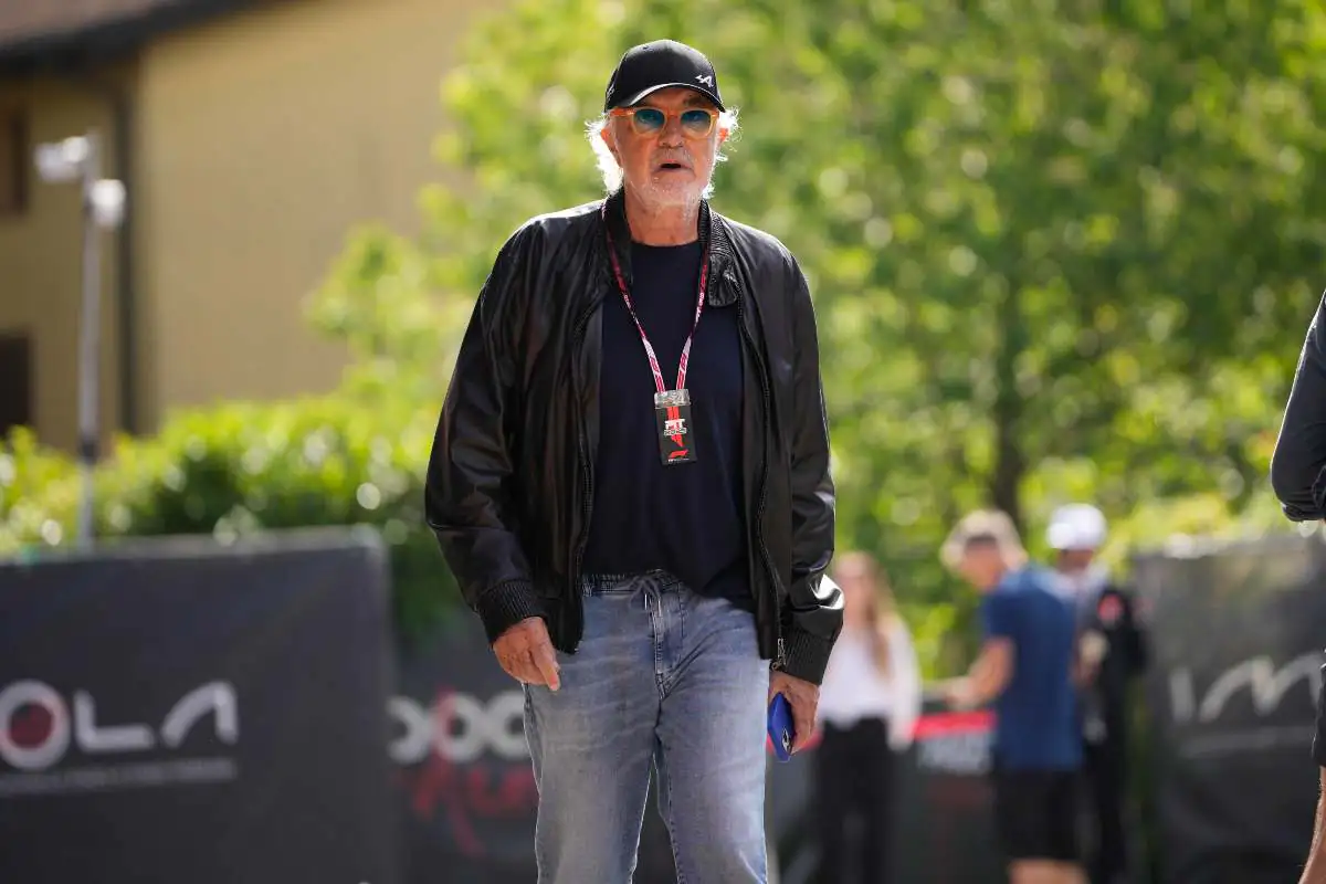 Briatore che cammina in un’area esterna durante un evento pubblico, con badge al collo e outfit casual.