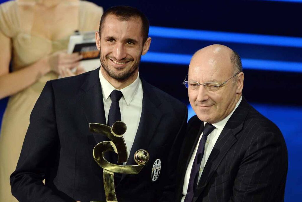 Giorgio Chiellini e Beppe Marotta sorridono durante una premiazione di calcio.