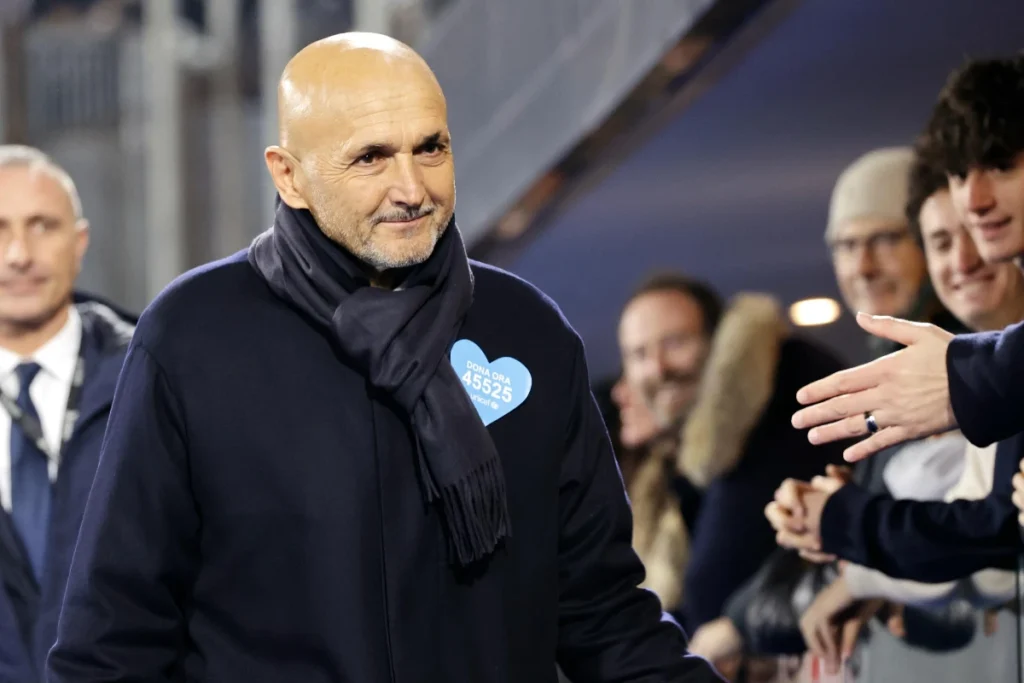 Luciano Spalletti con fascia azzurra durante una partita, in panchina circondato dallo staff