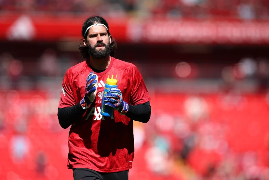 Alisson, portiere del Liverpool, durante il riscaldamento prima di una partita con fascia sulla fronte e guanti blu