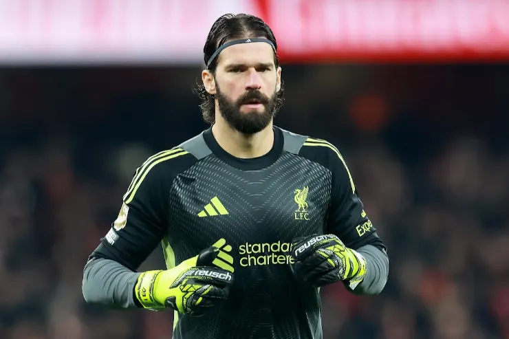 Alisson portiere durante una partita, con maglia nera e guanti gialli del Liverpool