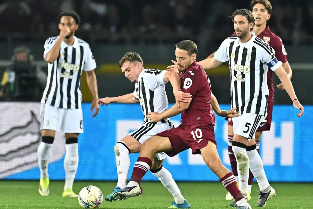 Giocatore del Torino con numero 10 contrasta il possesso palla contro difensori della Juventus durante la partita
