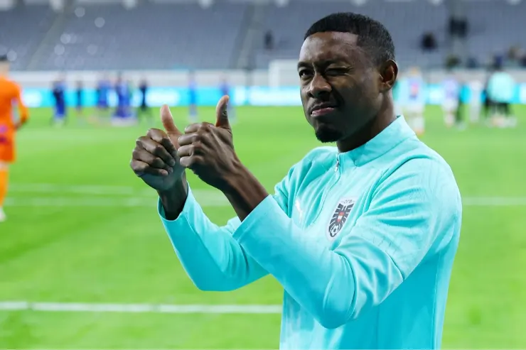 Alaba sul campo di allenamento in tuta azzurra, indicando con i pollici verso l'alto