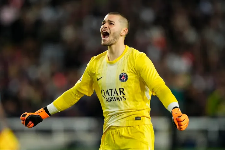 Portiere in divisa gialla PSG con braccia allargate esulta durante una partita di calcio