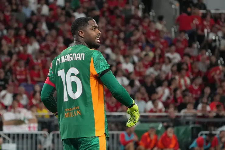 Maignan portiere in maglia verde con numero 16, durante una partita con pubblico sullo sfondo