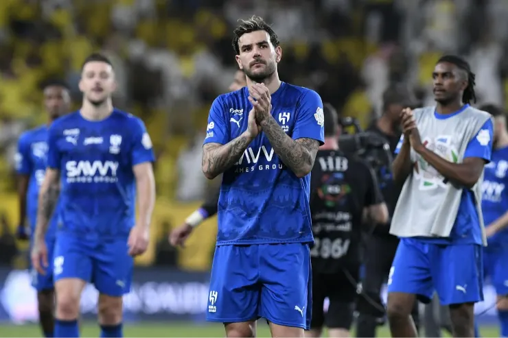 Theo Hernández in maglia blu durante una partita, con le mani giunte in segno di concentrazione