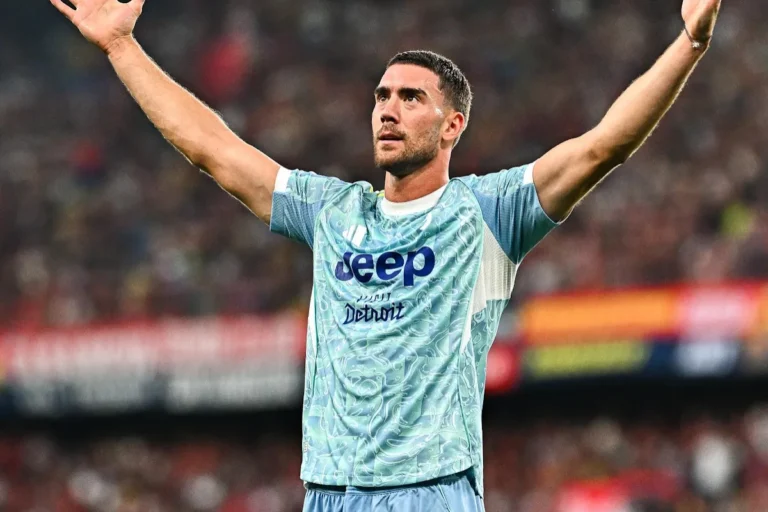Vlahovic esulta a braccia alzate in maglia Juventus azzurra durante una partita