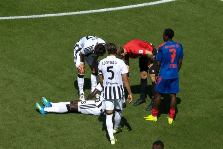Infortunio durante Basilea-Juventus, giocatore bianconero a terra circondato da staff medico e arbitro in campo