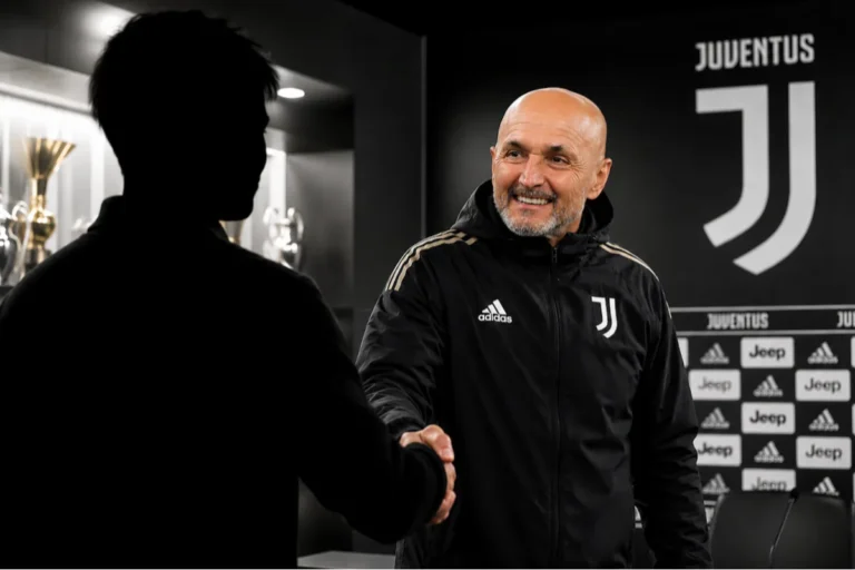 Allenatore Juventus in tuta Adidas durante una riunione nello spogliatoio, sullo sfondo il logo bianconero
