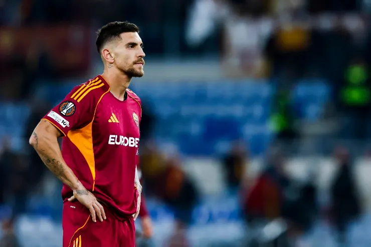 Pellegrini in maglia da calcio rossa durante una partita, in campo con lo stadio sullo sfondo