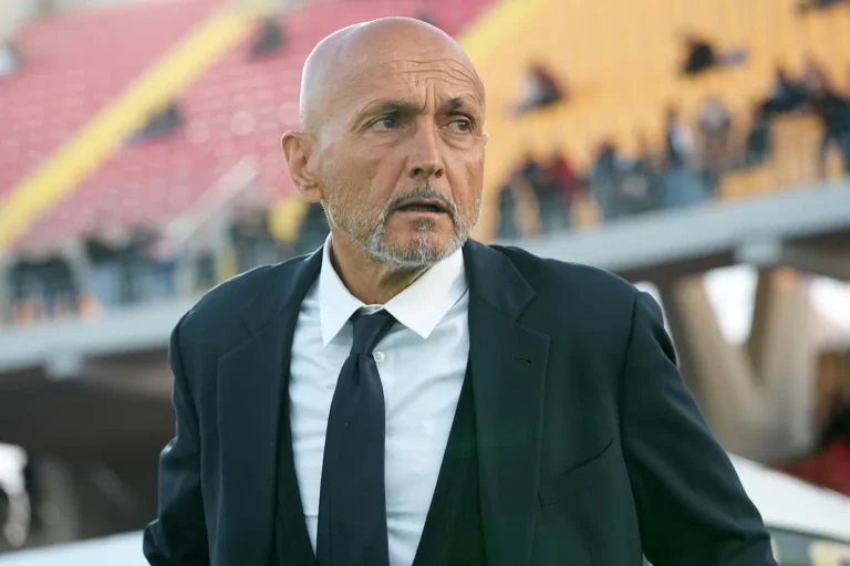 Luciano Spalletti in abito scuro e cravatta nera osserva dalla panchina durante una partita di calcio