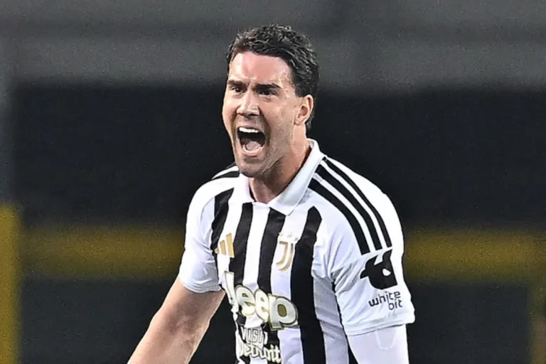 Vlahovic esulta durante una partita con la maglia della Juventus a righe bianche e nere