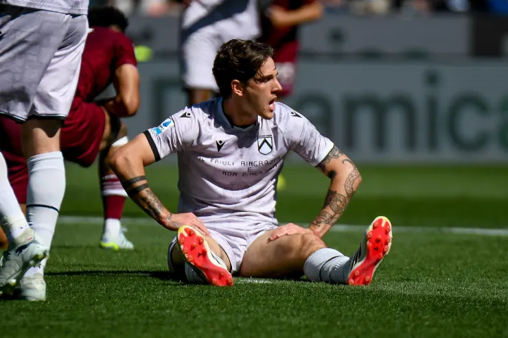 Zaniolo a terra durante la partita, in maglia bianca della Juventus con avversari in rosso sullo sfondo