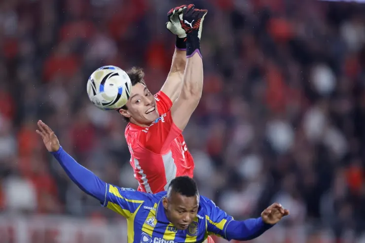 Beltran portiere del River Plate effettua una parata aerea durante una partita, con un difensore in maglia blu alle spalle