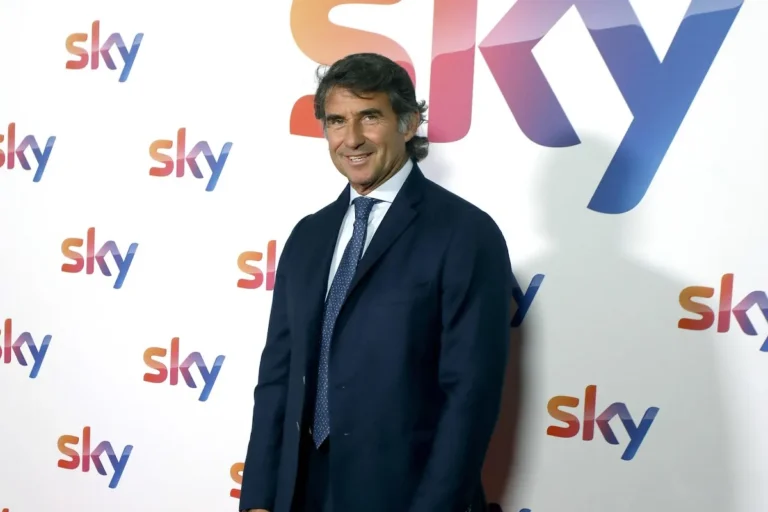 Giovanni Carnevali in abito scuro davanti al muro brandizzato Sky