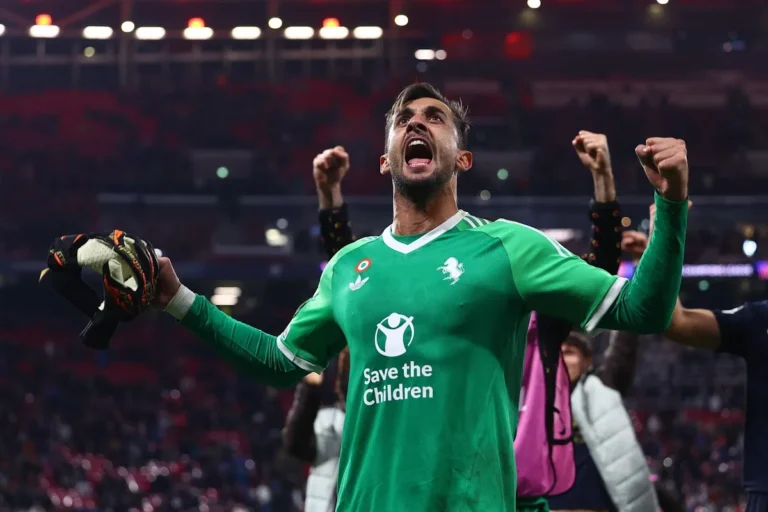Mattia Perin esulta in campo con la maglia verde da portiere, braccia alzate, indossando la divisa con sponsor Save the Children