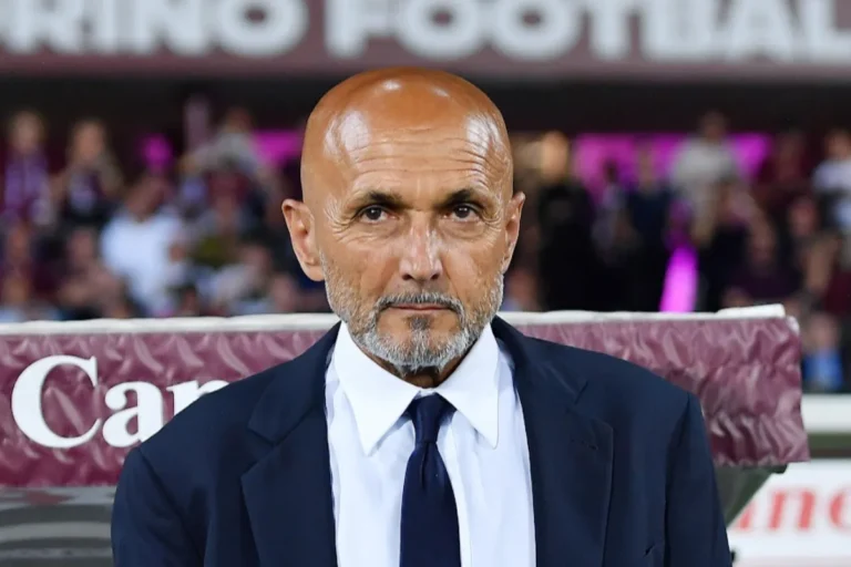 Luciano Spalletti in panchina durante una partita, indossa giacca blu scuro e cravatta