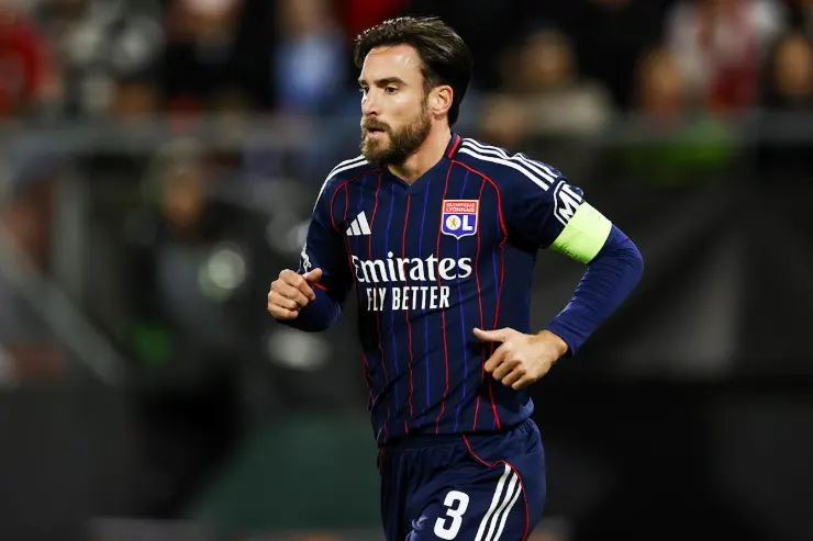 Tagliafico in maglia Olympique Lione corre sul campo indossando la fascia di capitano