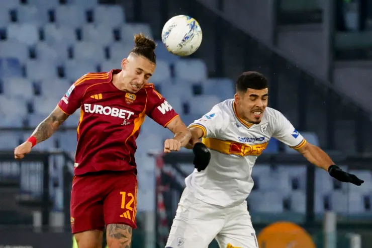 Tsimikas in azione durante una partita di calcio, salta per colpire di testa il pallone
