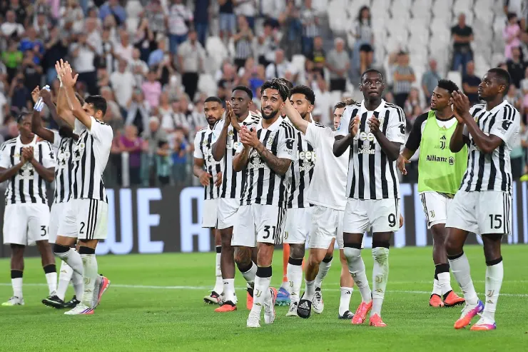 Giocatori della Juventus riuniti in campo durante una partita, indossano la divisa a righe bianche e nere
