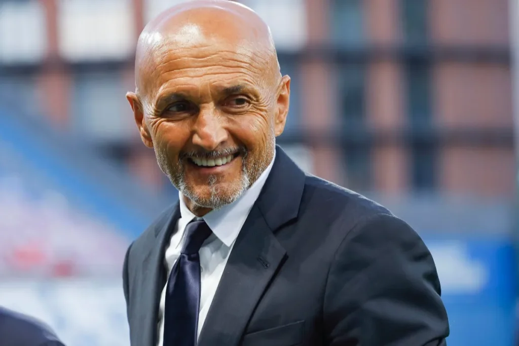 Luciano Spalletti sorride durante una partita, indossa completo blu scuro e cravatta