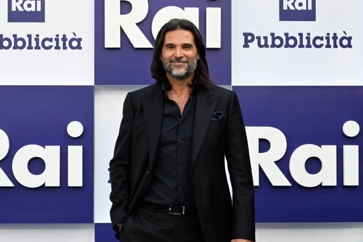 Adani in abito nero, davanti a un backdrop Rai