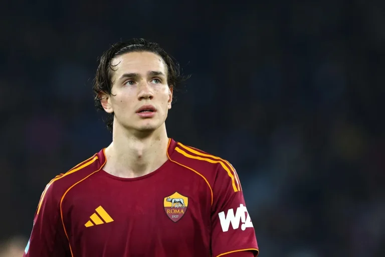 Ghilardi con maglia della Roma, capelli scuri e sguardo rivolto verso l'alto durante una partita