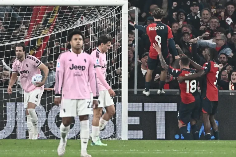 Giocatori della Juventus in maglia rosa delusi in primo piano mentre i giocatori del Genoa esultano sotto la curva rossoblù