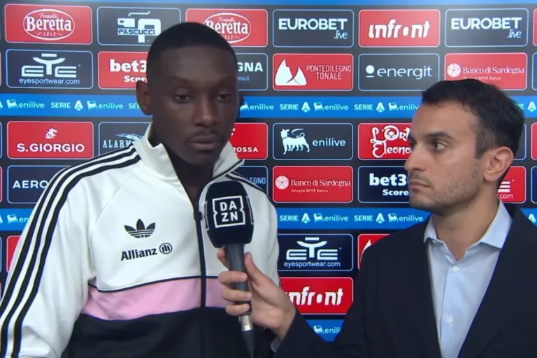 Kolo Muani con giacca bianca, nera e rosa Adidas intervistato da un giornalista DAZN a bordo campo Serie A