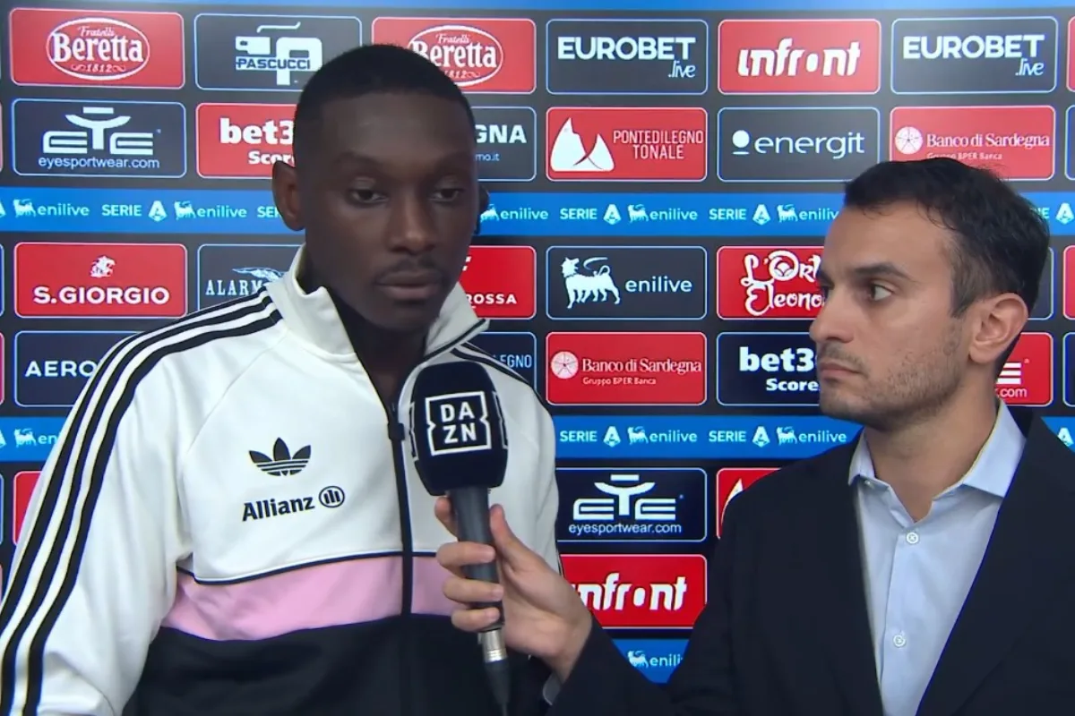 Kolo Muani con giacca bianca, nera e rosa Adidas intervistato da un giornalista DAZN a bordo campo Serie A
