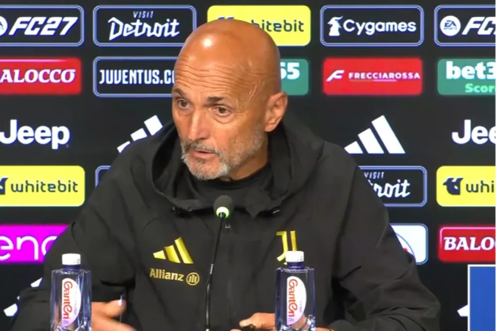 Spalletti parla in conferenza stampa con giacca Juventus davanti a un pannello sponsor