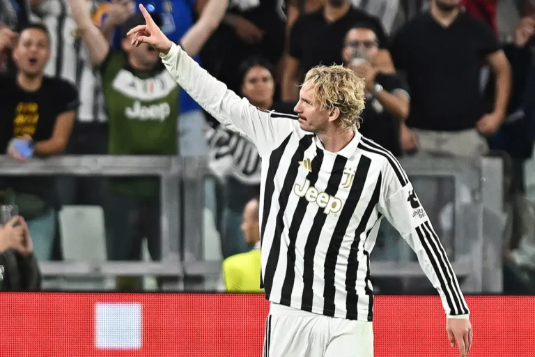 Giocatore della Juventus con maglia bianconera esulta durante la partita, pugno chiuso verso l'alto